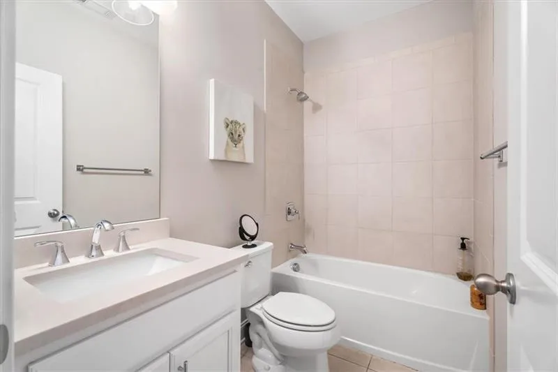 Full bathroom with vanity with extensive cabinet space, tile floors, toilet, and tiled shower / bath