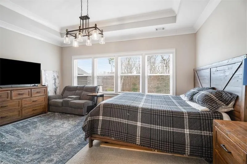 Bedroom featuring carpet flooring, a notable chandelier, a raised ceiling, and ornamental molding