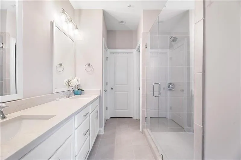 Bathroom featuring double sink, tile flooring, large vanity, and a shower with door