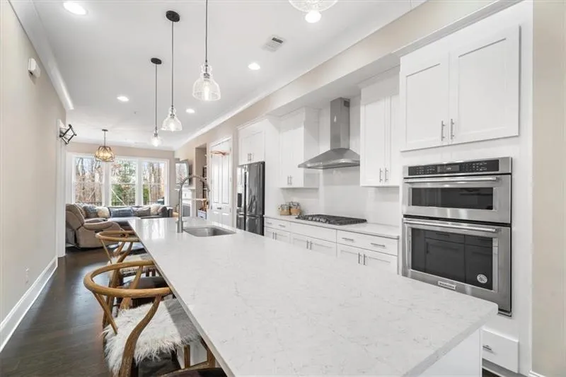 Kitchen featuring stainless steel appliances, sink, dark hardwood / wood-style flooring, wall chimney range hood, and hanging light fixtures