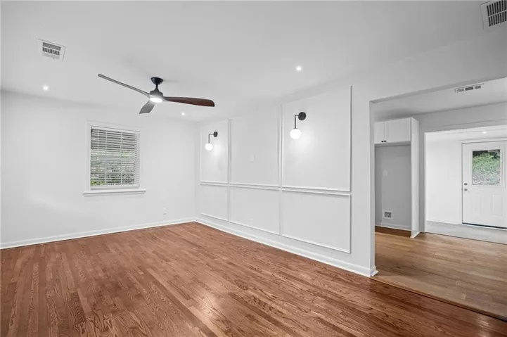 Spacious room featuring wood-finish flooring, a contemporary ceiling fan, recessed lighting, and decorative wall molding