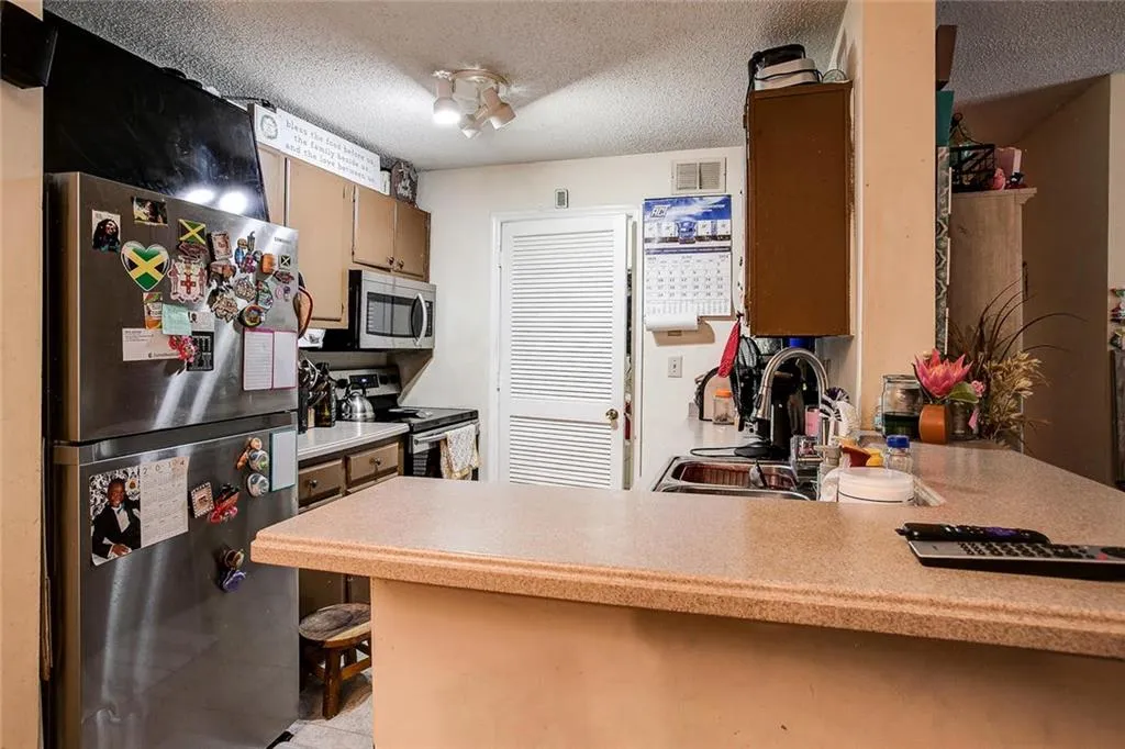 Kitchen with stainless steel appliances, sink, a textured ceiling, and kitchen peninsula