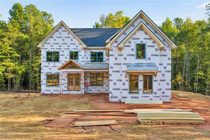 Two-story residence under construction with a dark shingle roof and multiple gables
