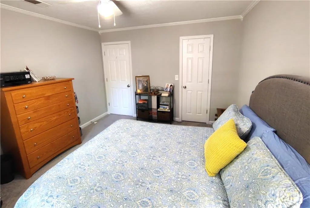 Carpeted bedroom 1with visible vents, baseboards, ceiling fan, and crown molding