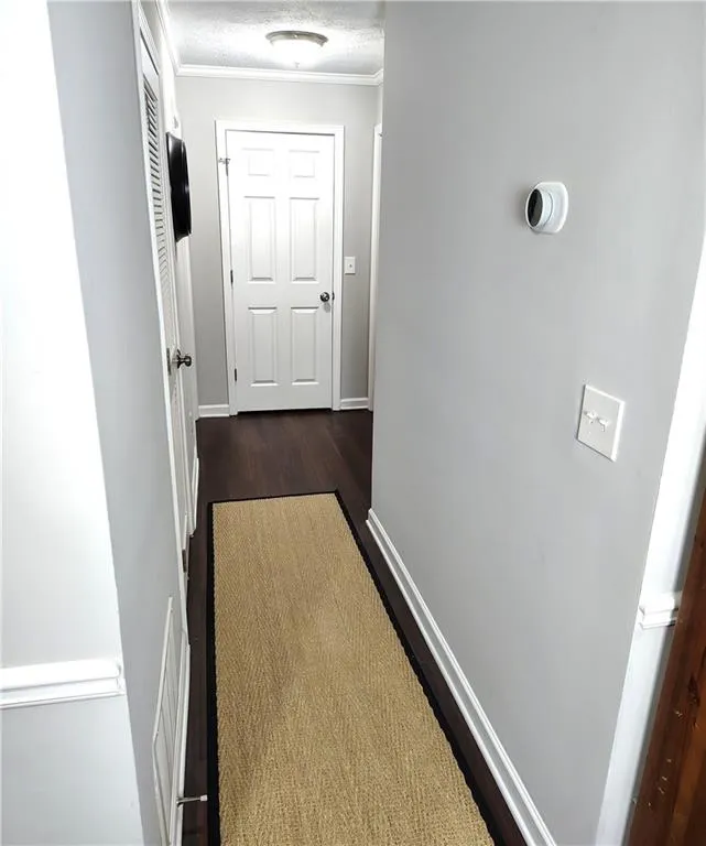Hall featuring baseboards, a textured ceiling, dark Wood-Look LVP floors, and crown molding