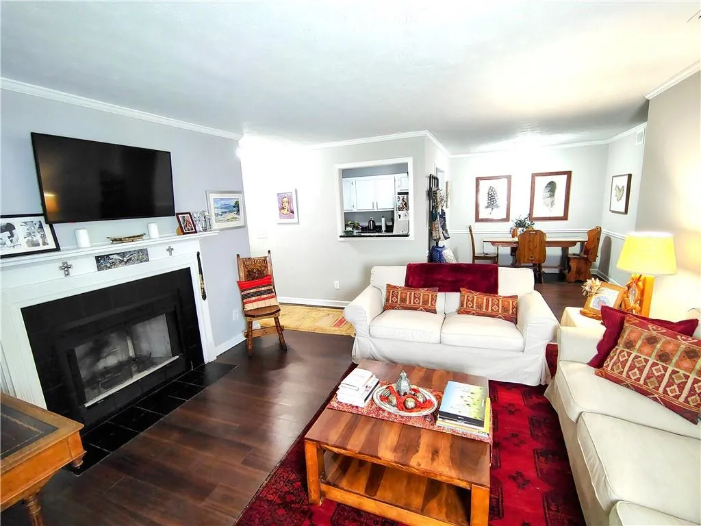 Living room featuring a fireplace with flush hearth, baseboards, ornamental molding, and Wood-Look  LVP floors