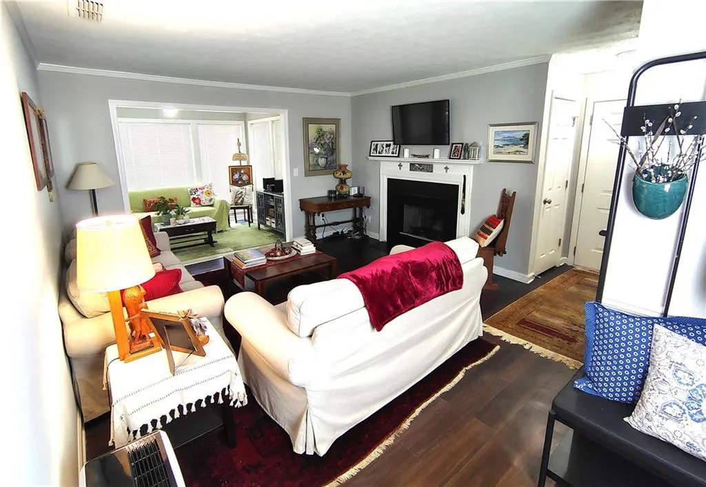 Living area with a fireplace, Wood-Look  LVP floors, visible vents, and crown molding