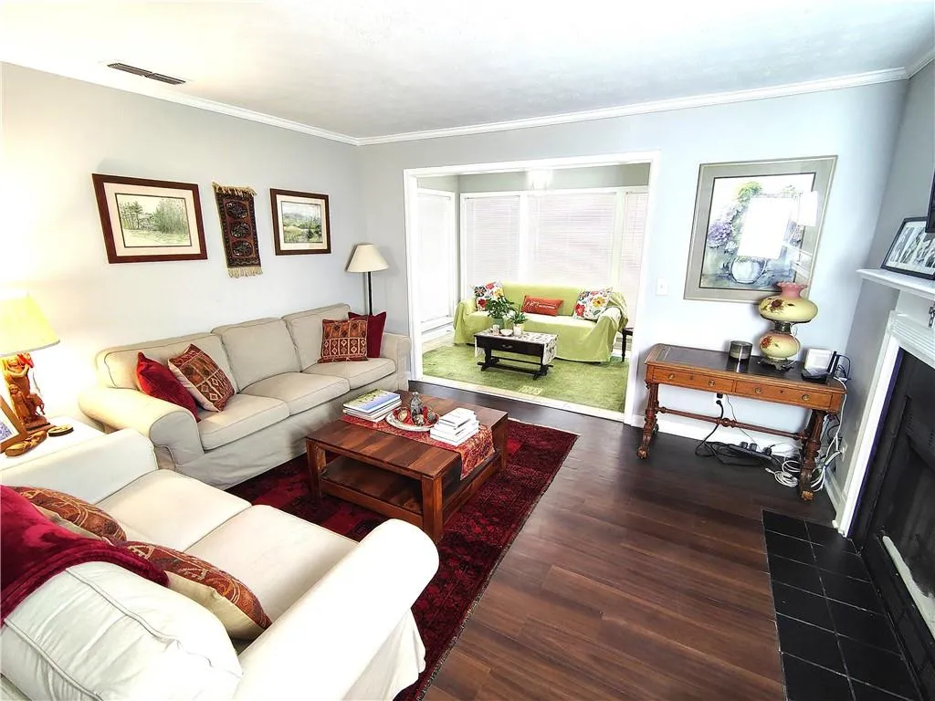 Living room featuring baseboards, ornamental molding,  Wood-Look  LVP floors, and visible vents