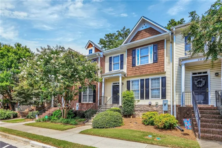 Colonial-style residence featuring a mixed exterior of brick and vinyl siding, peaked roofline with gabled dormers, and multi-pane double-hung windows