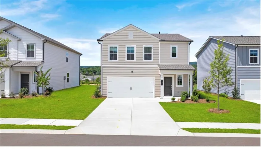 Traditional-style house with driveway, an attached garage, a shingled roof, and a front lawn