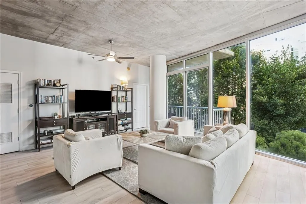 Living room featuring floor to ceiling windows, light wood-style floors, and ceiling fan