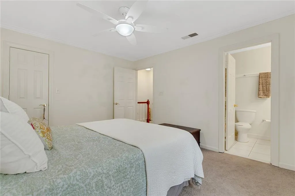 Tiled bedroom featuring crown molding, ceiling fan, connected bathroom, and a closet