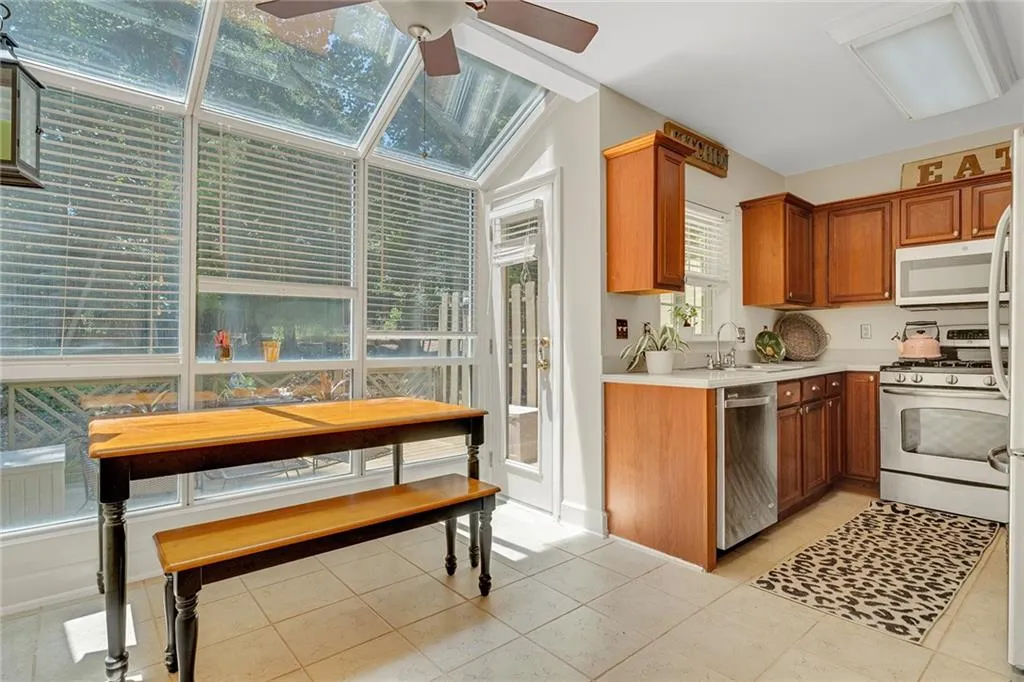 Kitchen featuring light tile patterned flooring, ceiling fan, white appliances, sink, and lofted ceiling