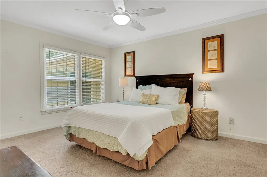 Carpeted bedroom featuring crown molding and ceiling fan