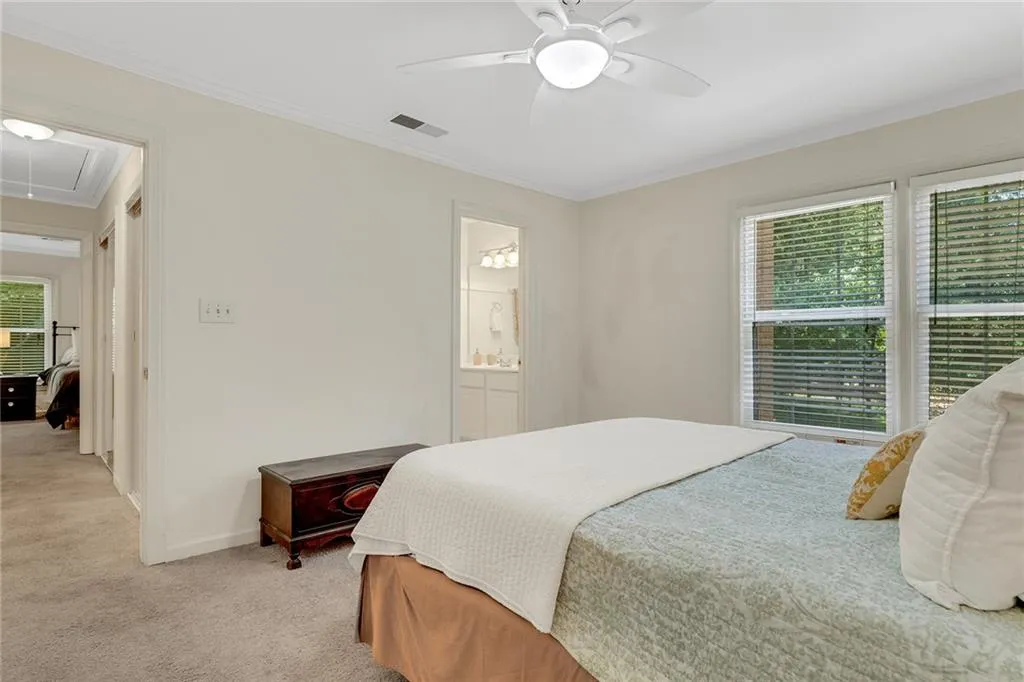 Bedroom featuring ceiling fan, light carpet, multiple windows, and ornamental molding
