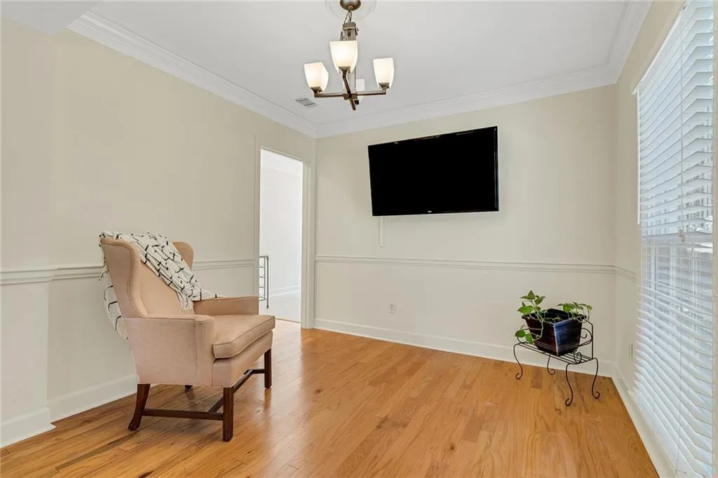Living area with an inviting chandelier, light hardwood / wood-style flooring, and ornamental molding