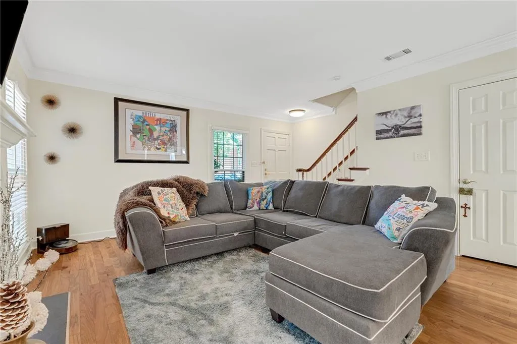 Living room with wood-type flooring and crown molding