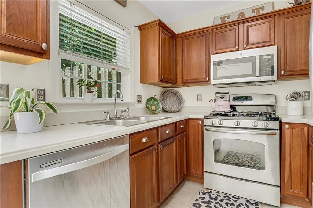 Kitchen featuring light tile patterned flooring, sink, and appliances with stainless steel finishes