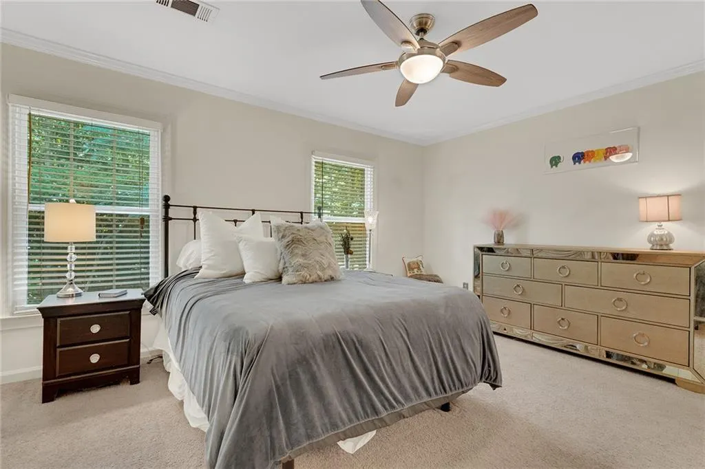 Carpeted bedroom with crown molding and ceiling fan