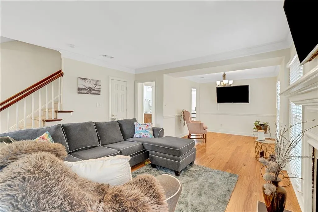 Living room with crown molding, a notable chandelier, and hardwood / wood-style floors