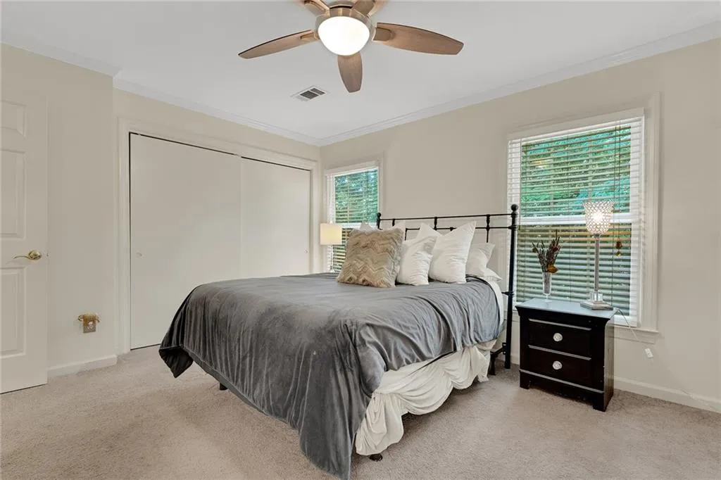 Carpeted bedroom with ceiling fan, ornamental molding, and a closet