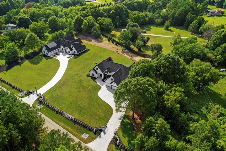 Expansive property featuring two distinct residences, each with a concrete driveway and lush green lawns