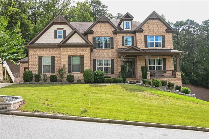 Brick exterior with multiple gables, covered porch, dormer window, and dark window shutters