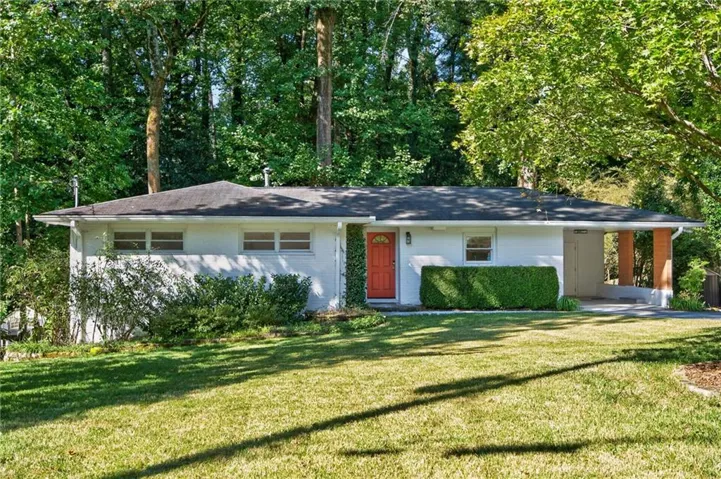 Single-story residence featuring a white painted exterior, a dark shingle roof, and a vibrant orange entry door