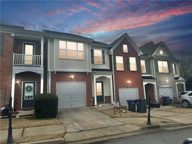 Brick and siding townhouse exterior featuring a single-car garage, covered entry, and a second-story balcony