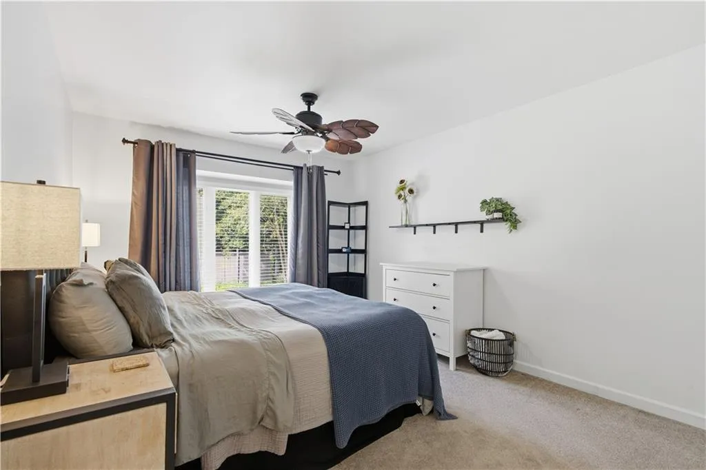 Bright room featuring a ceiling fan, light-colored carpeting, white walls, and a window with blinds