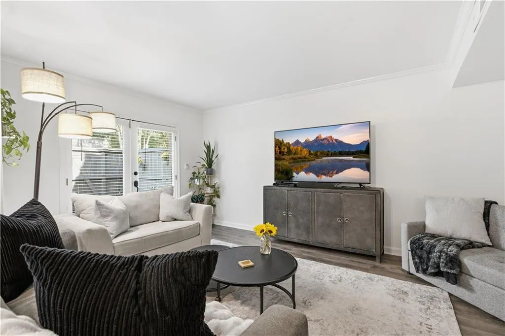 Wood-finish flooring, white walls, crown molding, and double glass doors with blinds