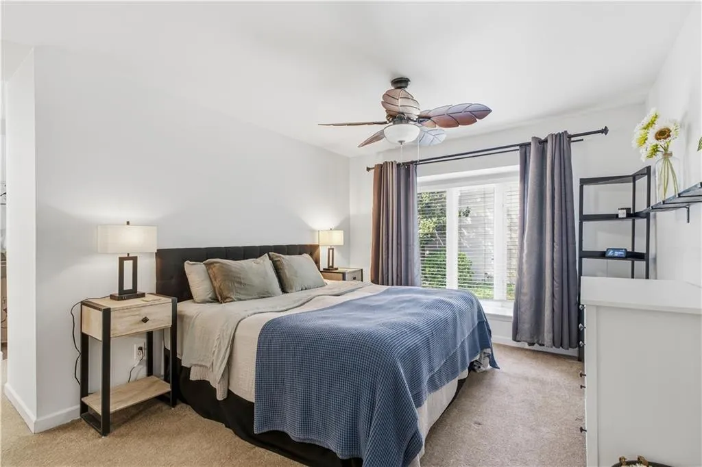 White walls, carpeted flooring, and a ceiling fan with integrated lighting