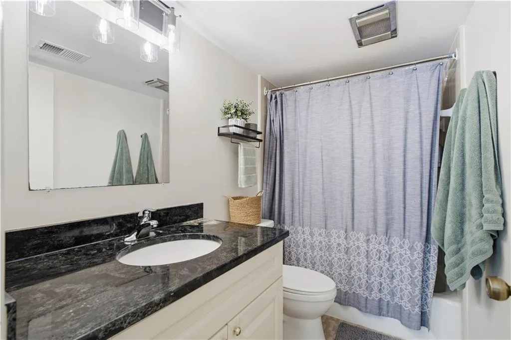 Vanity with dark countertop, white under-mount sink, and chrome faucet
