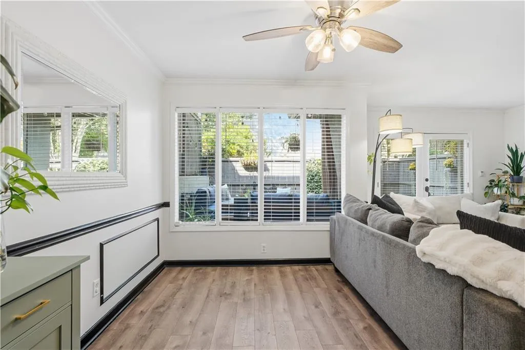 Wood-finish flooring with white baseboards, crown molding, and wainscoting