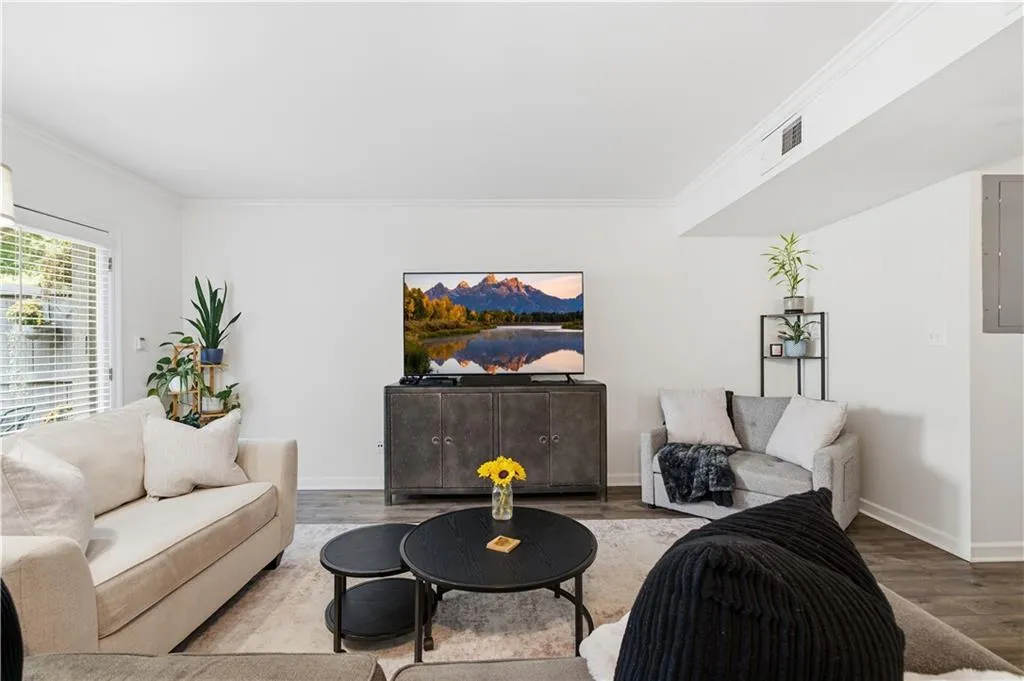 Bright living space featuring wood-finish flooring and crown molding