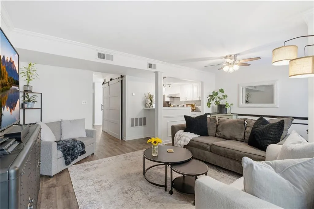 Spacious living area featuring wood-finish flooring, crown molding, and a ceiling fan