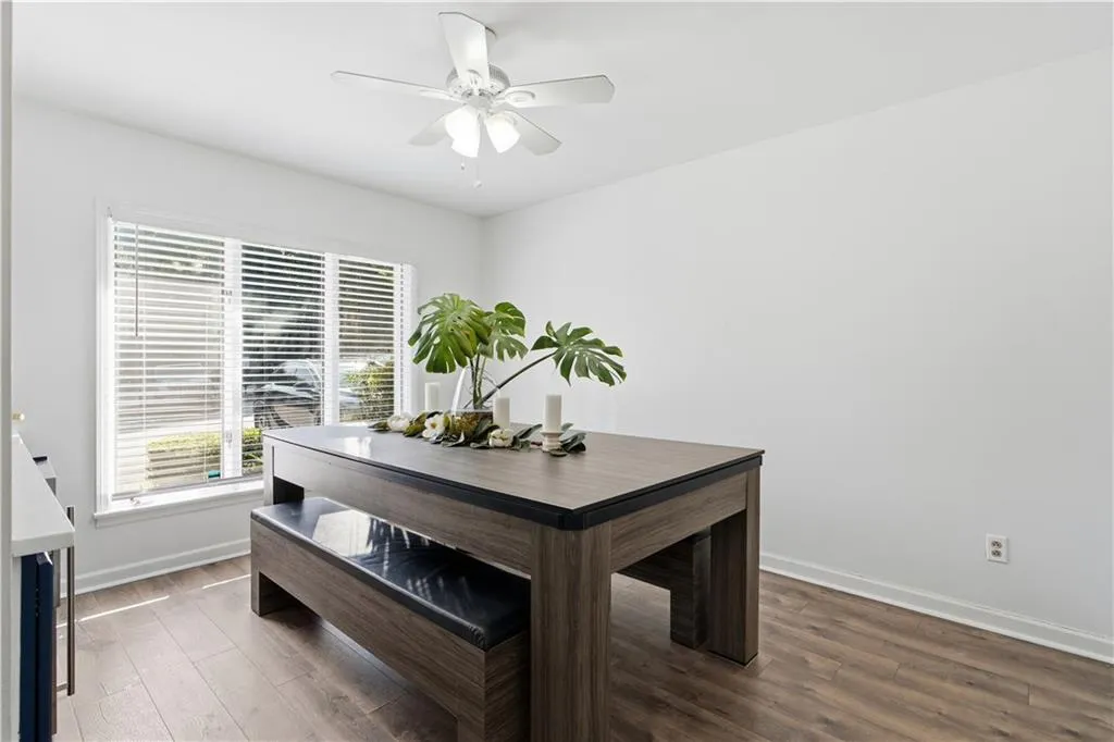Wood-finish flooring, white walls, and a ceiling fan with integrated lighting
