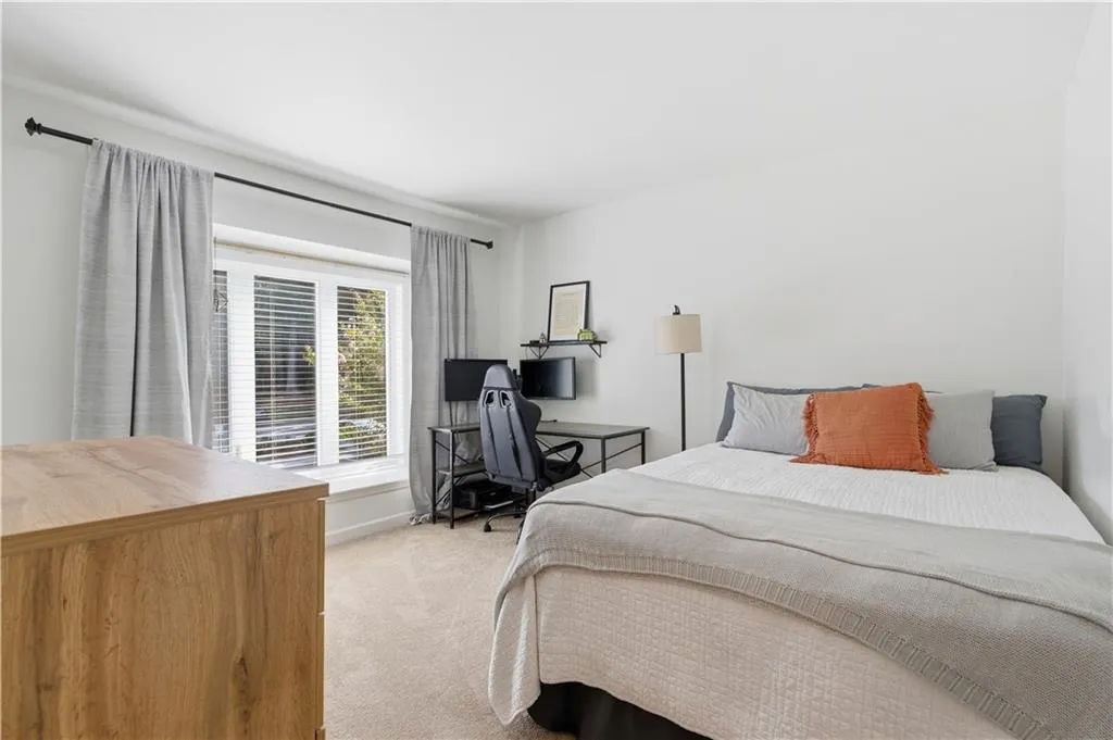 White wall paint, large window with blinds, light-toned carpeting, and a built-in shelf