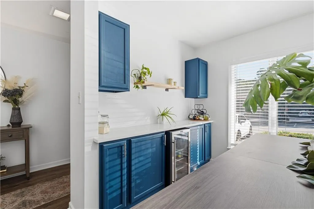 Built-in blue cabinetry, white countertops, built-in beverage refrigerator, wood-finish flooring, and a large window