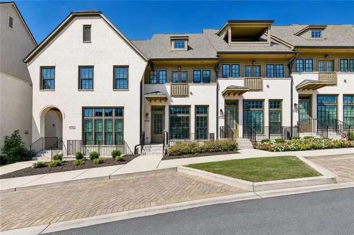 White brick exterior with dark-framed windows, multiple dormer windows, and a prominent arched entryway