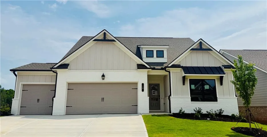 Contemporary home featuring a white brick and vertical siding exterior, a dark shingle roof, a two-car garage, a single dormer, and a covered entry