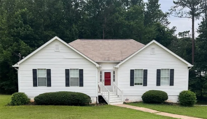 White siding exterior with a red front door, black window shutters, and a light brown shingle roof