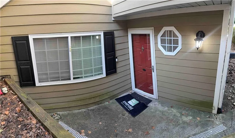 Red entry door with an octagonal accent window, complemented by an exterior wall sconce