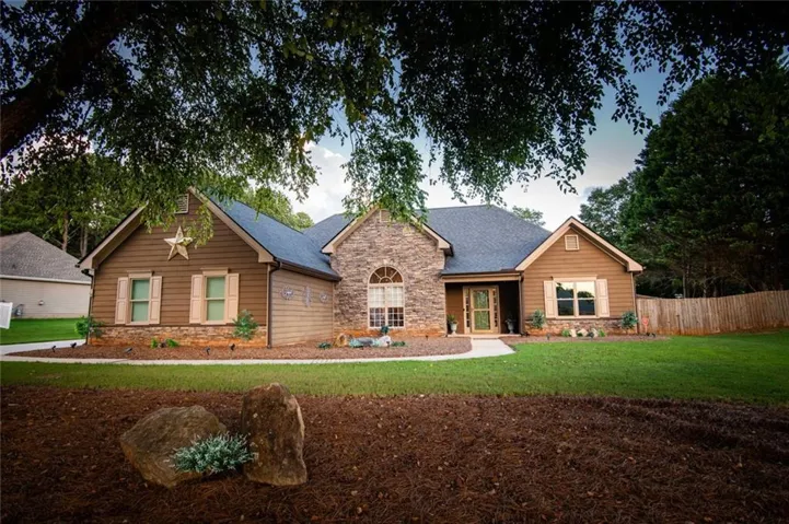 Ranch-style exterior featuring a stone facade, brown siding, a dark shingle roof, and a curved front walkway
