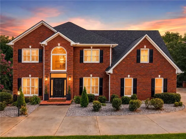 Brick exterior with a dark shingle roof, featuring multiple gables and white trim