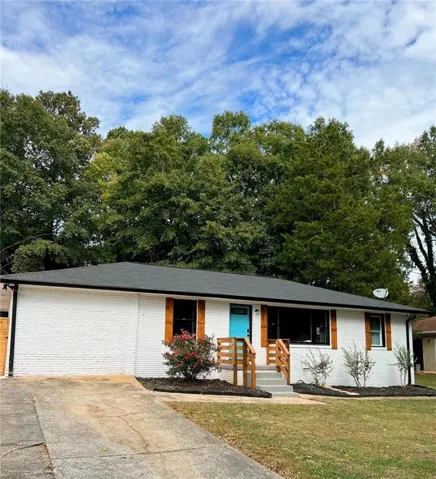 Ranch-style house featuring brick siding, covered porch, a front lawn, and driveway