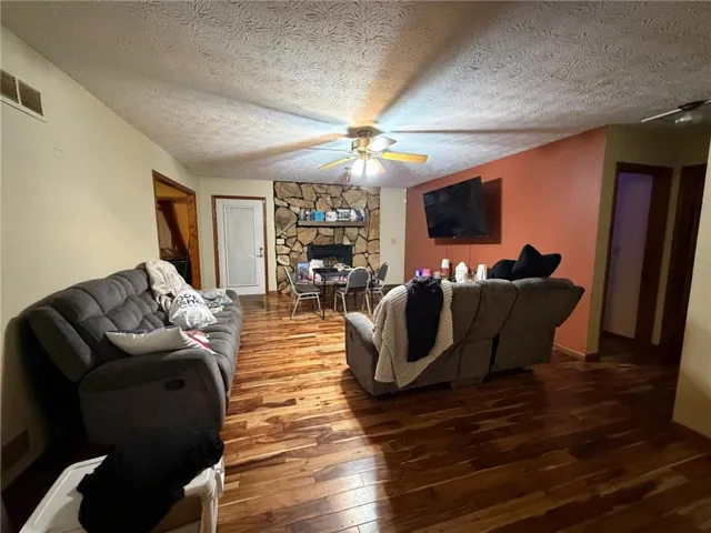 Living area featuring wood-finish flooring and a stone-clad fireplace