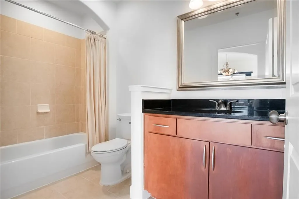 Full bathroom featuring shower / bath combo with shower curtain, toilet, tile patterned floors, and vanity