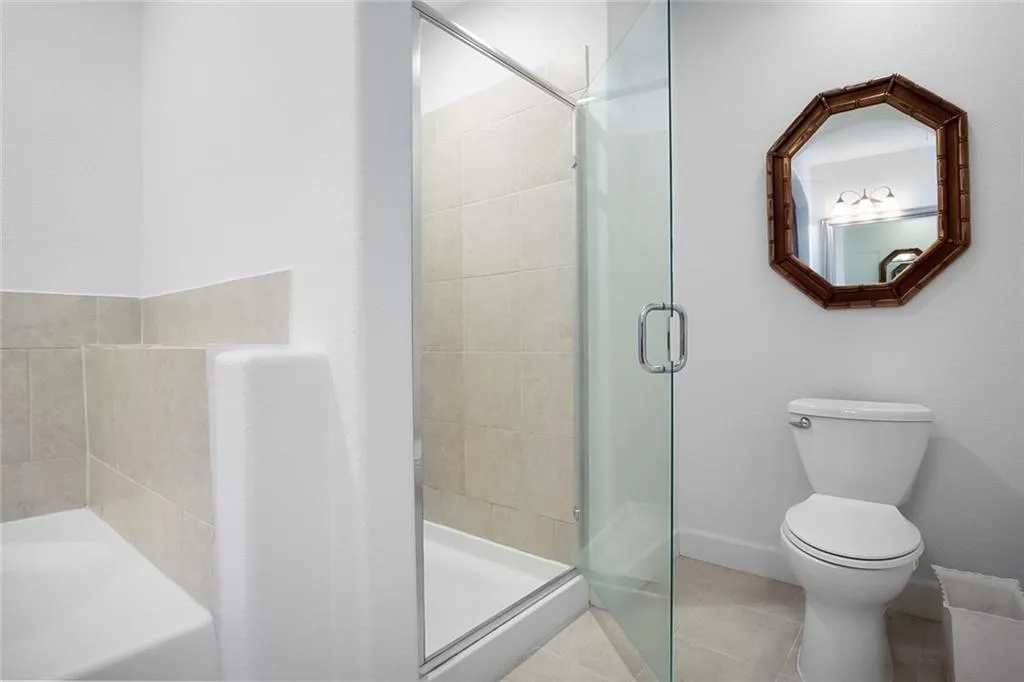 Full bath with a stall shower, tile patterned floors, toilet, a garden tub, and baseboards