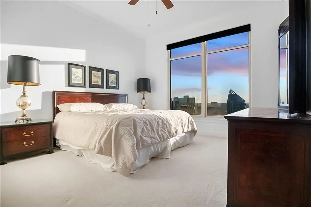 Carpeted bedroom featuring a ceiling fan, access to outside, vaulted ceiling, and a city view